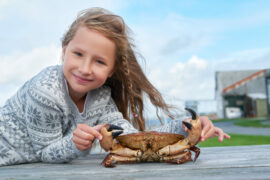 Young girl by the ocean with a crab