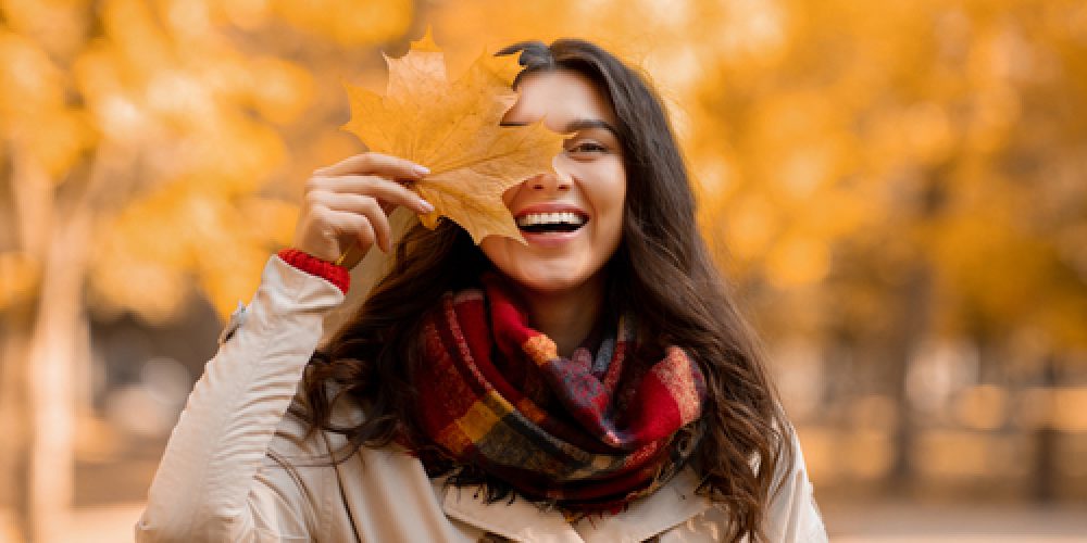 Smiling woman outside with a big leaf over her right eye